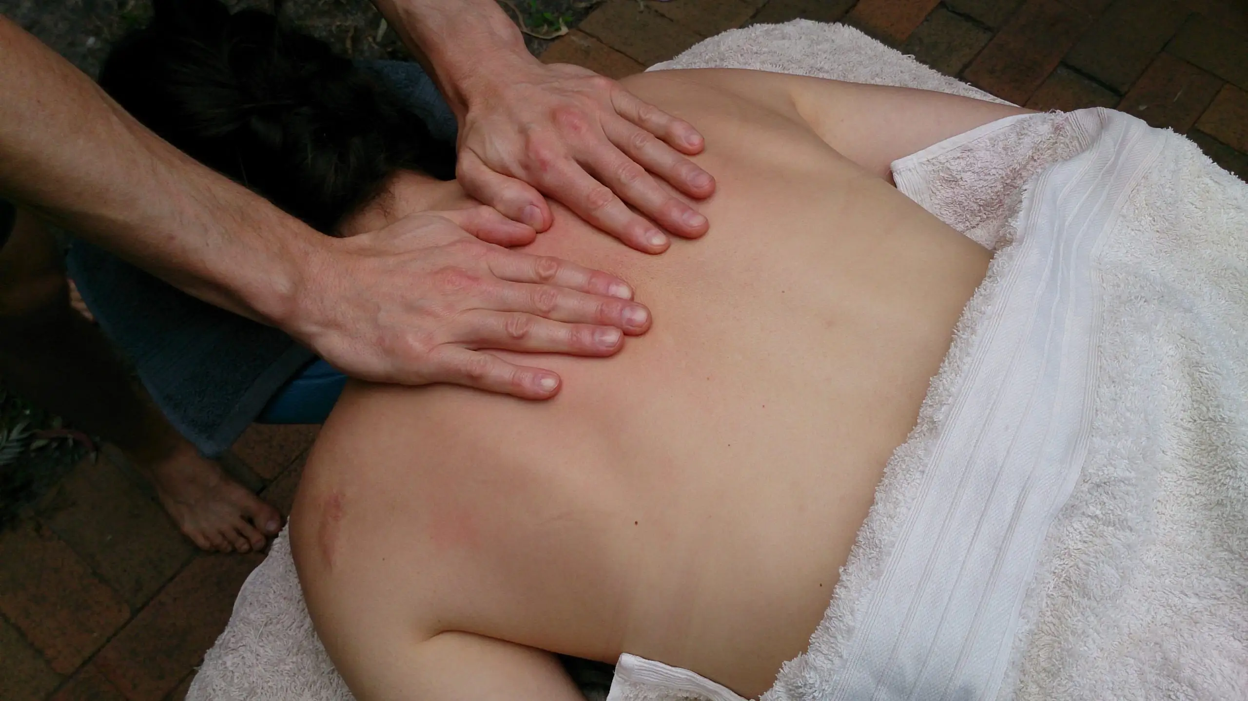 A massage therapist working on a client’s upper back