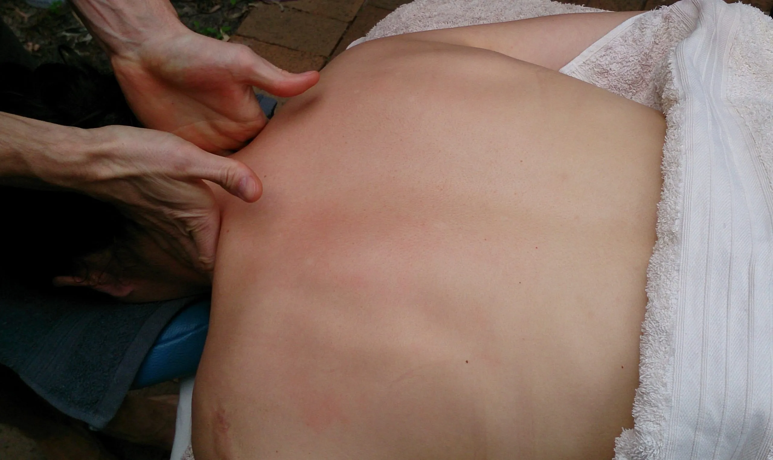 A massage therapist’s hands on a client’s back